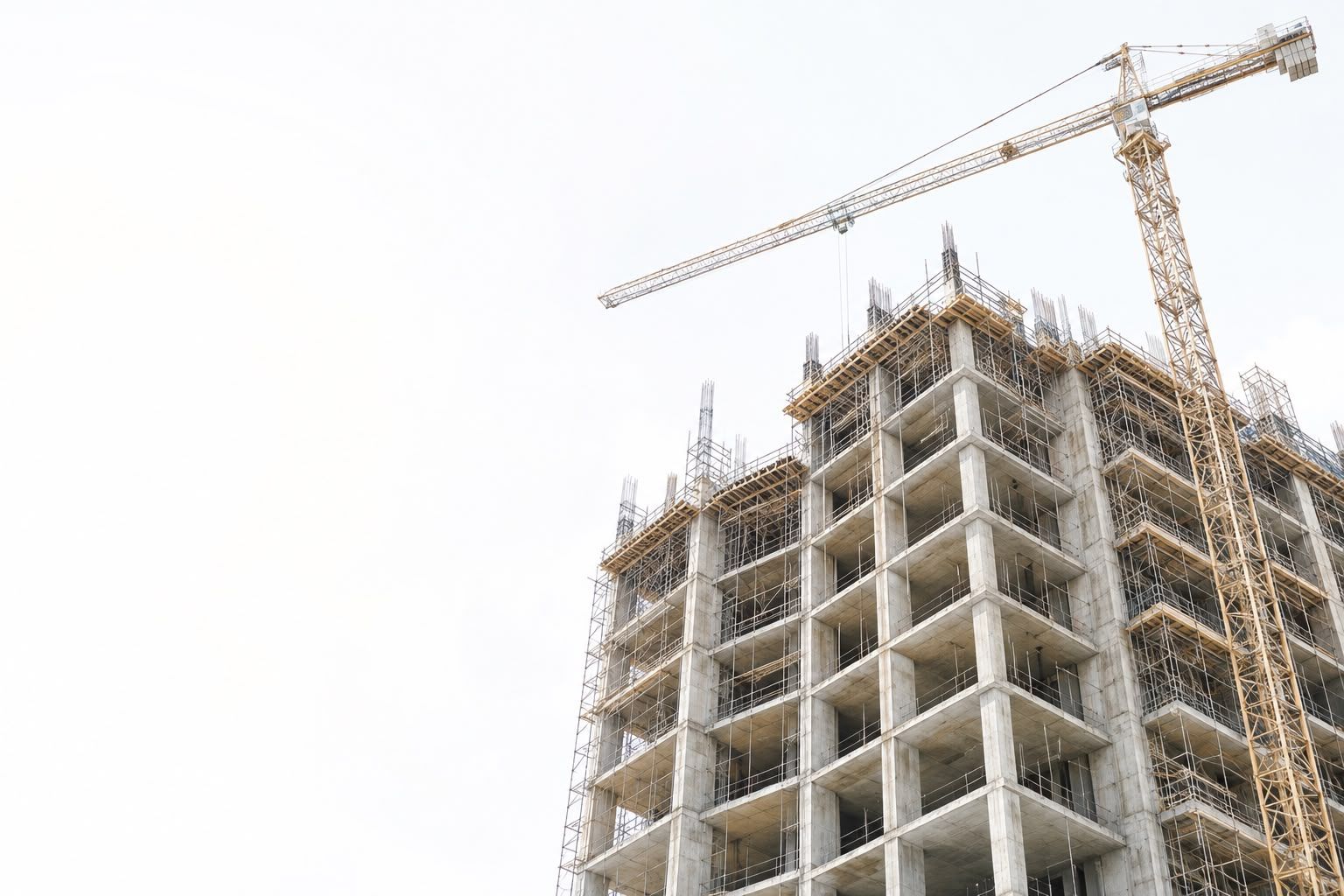 The concrete frame of a building under construction, with a tower crane beside it